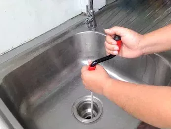 main d'une personne qui débouche un évier