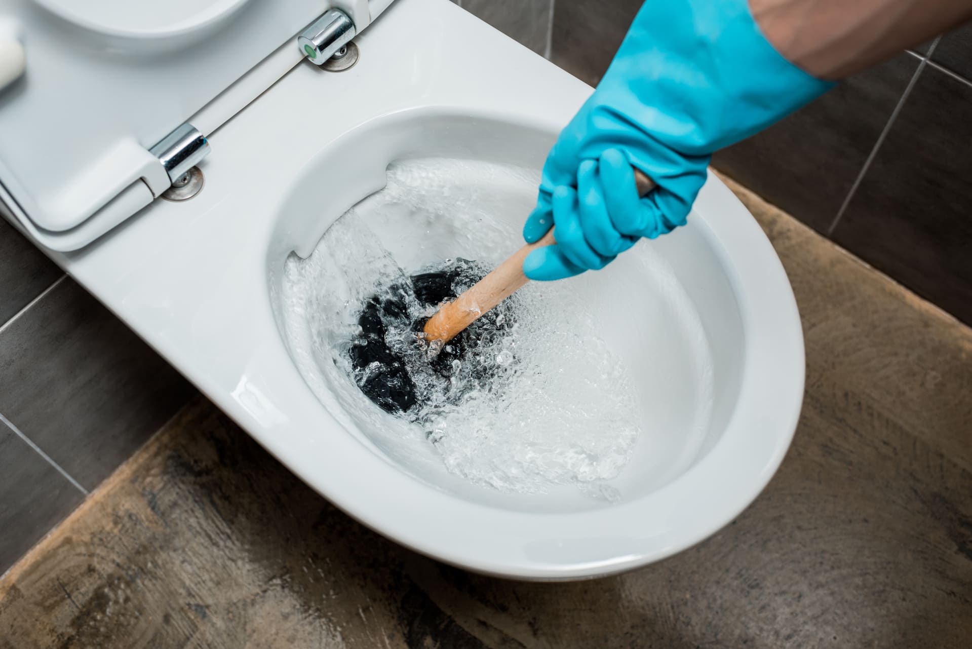 personne qui débouche les toilettes avec une ventouse