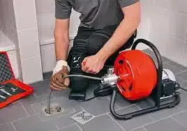 homme accroupi qui débouche une canalisation